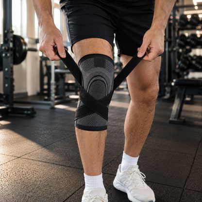 Un homme ajuste une genouillère de compression avec sangles à boucle en salle de sport pour un soutien et une stabilité supplémentaires pendant l'entraînement.
