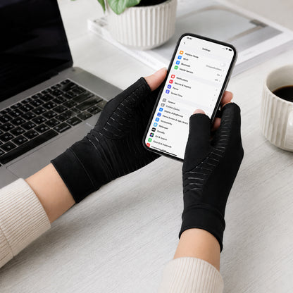 Une personne utilise des gants de compression en cuivre noirs en utilisant son téléphone.
