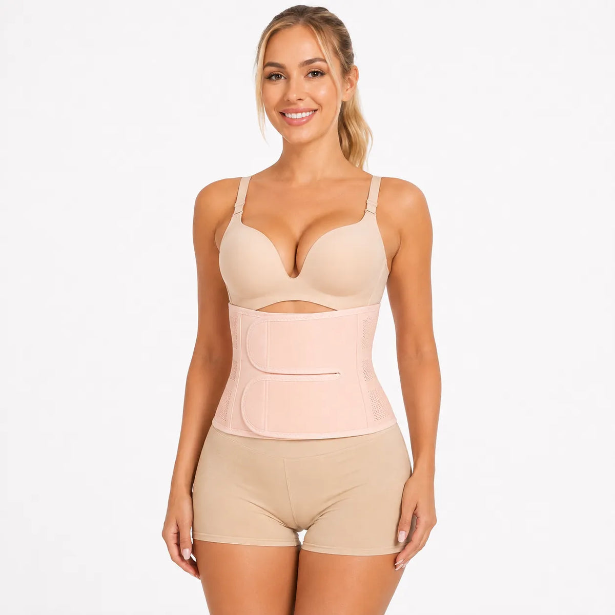 La femme porte un tailleur beige avec une coupe ajustée et une compression réglable autour de la taille.